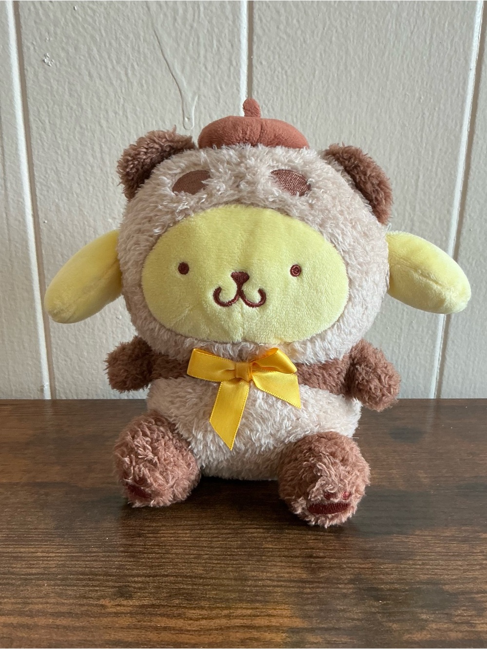 a Sanrio 2024 Pompompurin in Brown Panda Kigurumi Stuffed Plush Toy